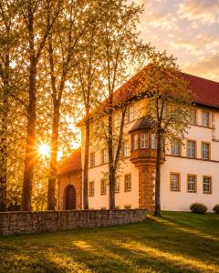 a house with the sun setting behind it at Schlosshotel am Hainich in Hörselberg-Hainich