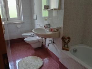 a bathroom with a sink and a toilet and a tub at Casa Defrancesco - with terrace in Moena +18 photos