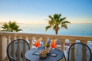 a table with wine glasses on a balcony with the ocean at Hotel Orizzonte in Letojanni +20 photos