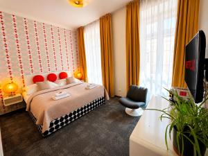 ein Schlafzimmer mit Bett, Fernseher und Stuhl in der Unterkunft LH Vintage Design Hotel Sax in Prag