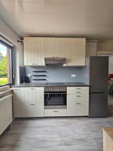 a kitchen with white cabinets and a stainless steel refrigerator at FeWo Zimmer Waldmohr in Waldmohr