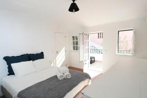 a white bedroom with a bed and a window at Villa Bocage in Setúbal