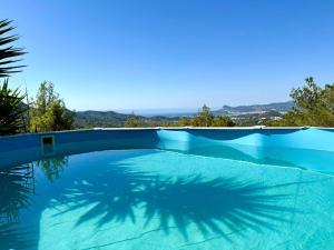 a blue swimming pool with a palm tree shadow at Villa Sa Guaita in Sant Josep de sa Talaia