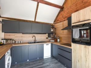 a kitchen with blue cabinets and a brick wall at Cart House Barn - Uk49802 in Morville