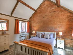 a bedroom with a bed and a brick wall at Cart House Barn - Uk49802 in Morville +17 photos