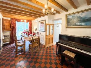 a dining room with a table and a piano at Y Ddol in Llansannan