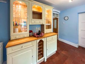 a kitchen with white cabinets and a counter at Y Ddol in Llansannan +16 photos
