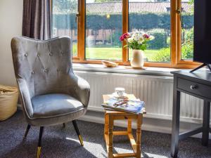 a chair and a table in front of a window at Dippers in Smallburgh