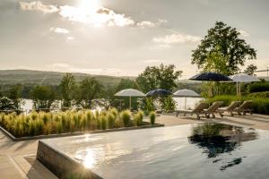 a swimming pool with chairs and umbrellas on a patio at Seezeitlodge Hotel & Spa in Gonnesweiler