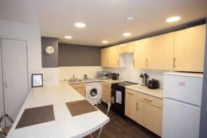 a kitchen with wooden cabinets and a washer and dryer at The Art Flat Glasgow in Glasgow +16 photos