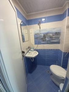 a blue and white bathroom with a toilet and a sink at Къща за гости "Адам и Ева" in Kavarna