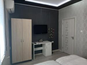 a bedroom with a bed and a desk and a tv at Къща за гости "Адам и Ева" in Kavarna