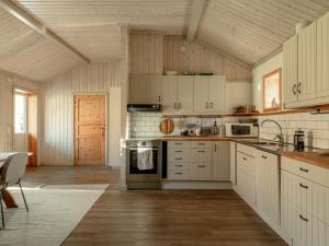 a kitchen with white cabinets and a wooden ceiling at Siljansnäs Stugby in Siljansnäs