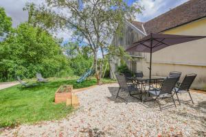 a patio with a table and chairs and an umbrella at Le charme du moulin in Beauvoir-sur-Sarce