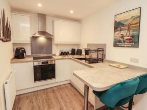 a kitchen with white cabinets and a table with blue chairs at Hidden Gem in Windermere