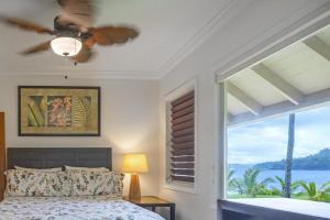 a bedroom with a ceiling fan and a bed with a window at Hanalei Colony Resort H4 in Hanalei