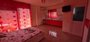 ein Schlafzimmer mit einem Bett und eine Küche mit roten Schränken. in der Unterkunft Hotel Vela Mare in Borsh