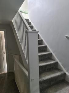 a staircase in a home with white railings and grey stairs at Fv Dwelling in Hucknall