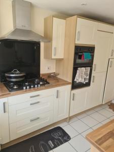 a kitchen with white cabinets and a stove top oven at Fv Dwelling in Hucknall