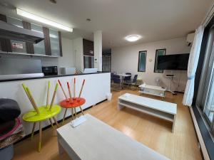 a living room with tables and chairs and a flat screen tv at Outdoor Station 秋谷 in Yokosuka