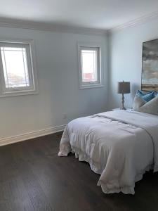 a white bedroom with a bed and two windows at HomeNet in Toronto