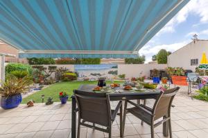 a table with chairs on a patio with a blue ceiling at Chambre D'hôtes Le Retour De Plage in Olonne-sur-Mer