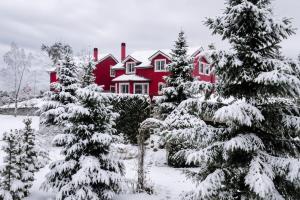 a red house with snow covered trees in front of it at Tre Bujtinat Gjinar in Elbasan