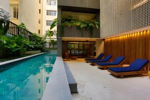 a pool with blue lounge chairs next to a building at Azure Loft: Sea & Luxury in Rio de Janeiro