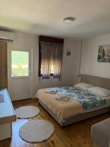 a bedroom with a bed and a window and two rugs at WIN apartment in Plužine