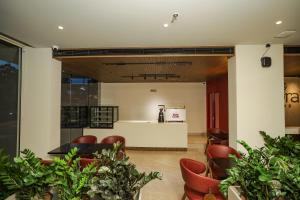 a lobby with red chairs and a counter at Alora Grand Hotel Calicut in Kozhikode