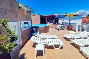 a patio with white lounge chairs and a pool at Happy Hotel Ancoradouro in Porto Seguro