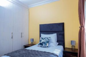 a bedroom with a bed with a blue headboard at Mainway home in Harare