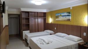a bedroom with two beds and a yellow wall at Happy Hotel Ancoradouro in Porto Seguro