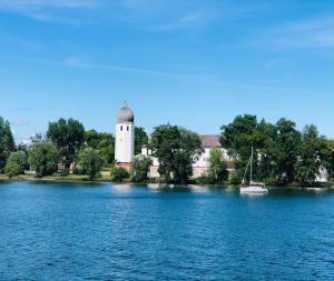 a lighthouse on the shore of a lake with a boat at Apartment Bergblick in Frasdorf