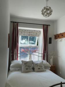 a bedroom with a bed with a window and a chandelier at Middle Cottage in Middleham