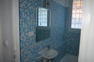 a blue tiled bathroom with a sink and a mirror at Casă de oaspeți autentică în Transilvania in Izvoru Mureşului +7 photos
