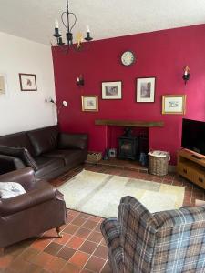 a living room with a couch and a red wall at Middle Cottage in Middleham