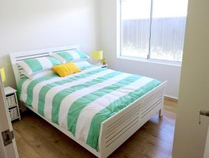 a white bedroom with a bed with green and white sheets at Contemporary Cove - Quindalup in Quindalup