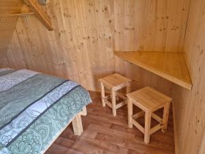 a room with a bed and two tables in a log cabin at Glamping Gril in Ljubno