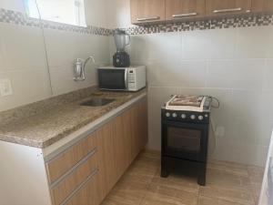 a small kitchen with a sink and a microwave at Red Coral Apts in Coroa Vermelha