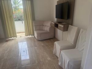 a living room with a chair and a television at Red Coral Apts in Coroa Vermelha