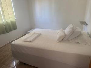 a bed with white sheets and pillows in a room at Red Coral Apts in Coroa Vermelha