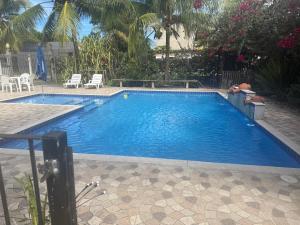 a large swimming pool in a yard with chairs at Red Coral Apts in Coroa Vermelha