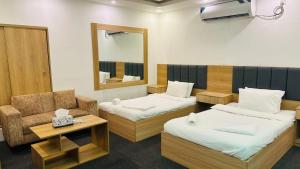 a room with two beds and a chair and a mirror at Hotel Marvellen Inn Ltd in Dhaka