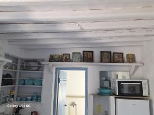 a kitchen with a shelf with pictures and a microwave at Ancienne ferme traditionnelle in Katavatí +7 photos