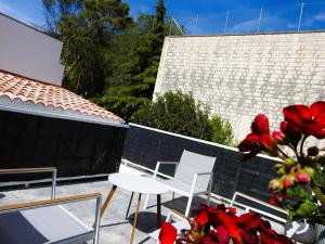 a patio with white chairs and a table and red flowers at Casa Rural Isabel y Luis in Chiloeches