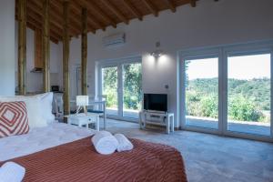 a bedroom with a bed and a tv and windows at Quinta da Barradinha in Odemira