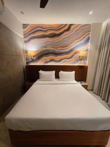 a bed in a room with a painting on the wall at Krishna Palace Hotel , Ulhasnagar in Ulhāsnagar +2 photos