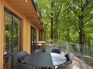 a room with a table and chairs on a balcony at Forest Lodges in Betws-y-coed