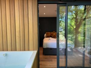a bathroom with a tub and a bedroom with a bed at Forest Lodges in Betws-y-coed